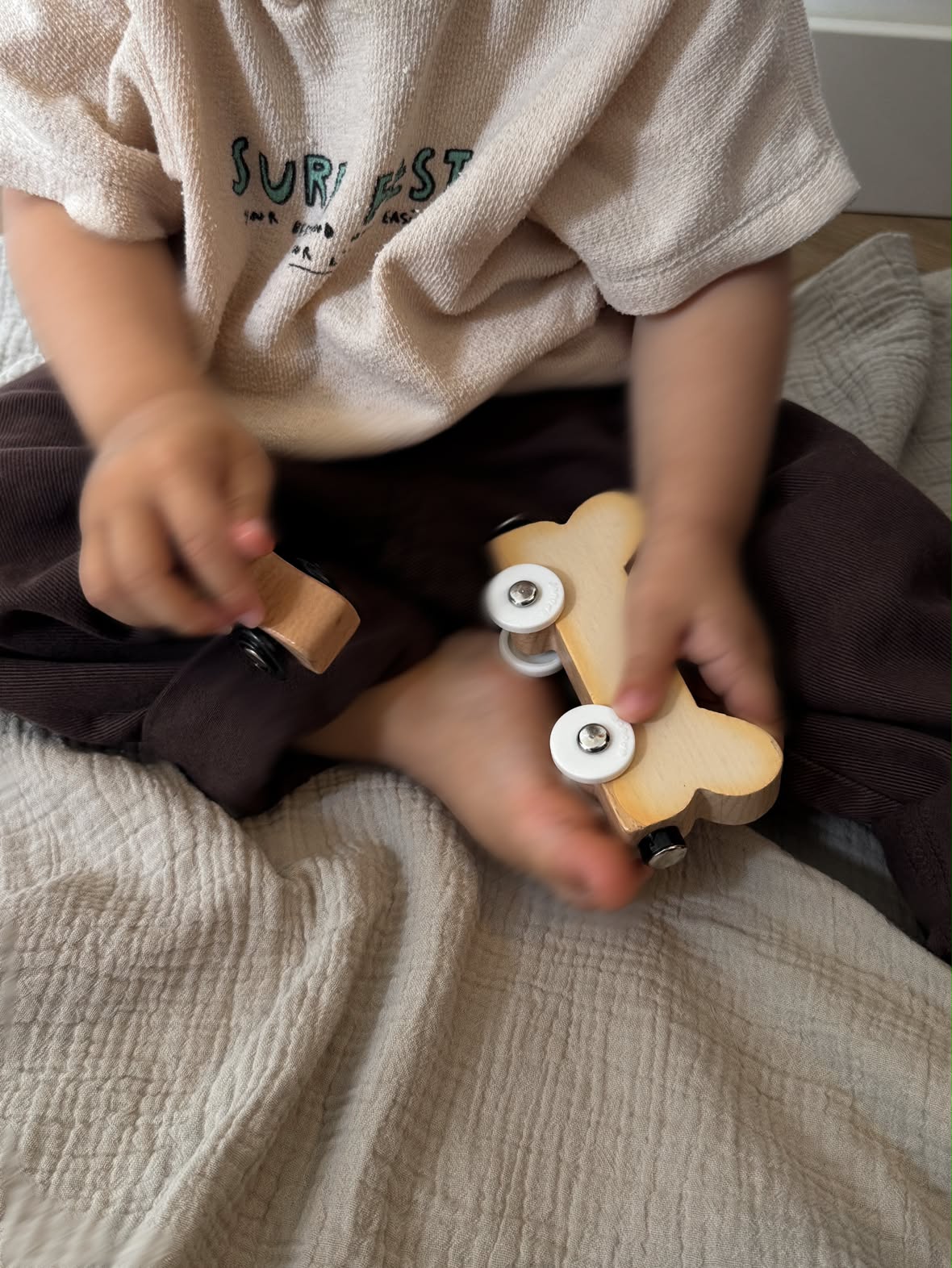 Les mains d'un enfant qui joue avec une petite voiture en bois