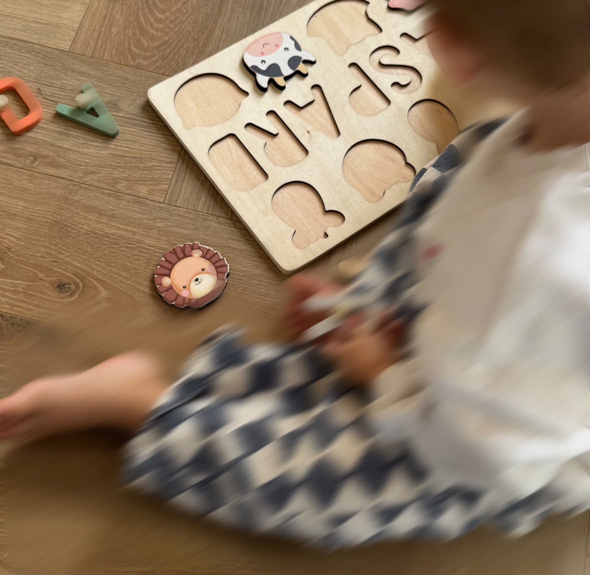 Un enfant joue avec un puzzle prénom en bois